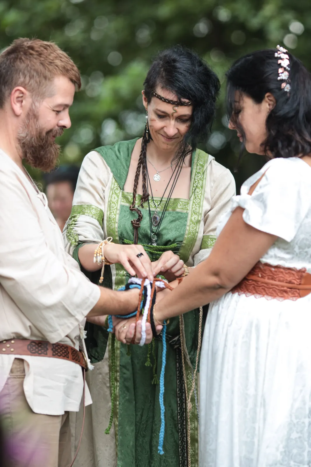 Estella Balbastre célèbre un mariage druidique : rituel du handfasting, les mains des mariés liées par des cordons colorés